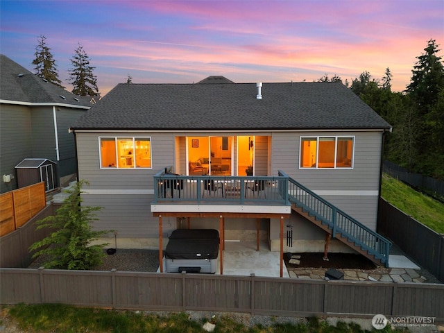 back of house at dusk with a fenced backyard, a patio area, stairway, and a deck