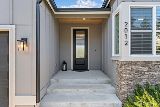 doorway to property featuring board and batten siding and stone siding