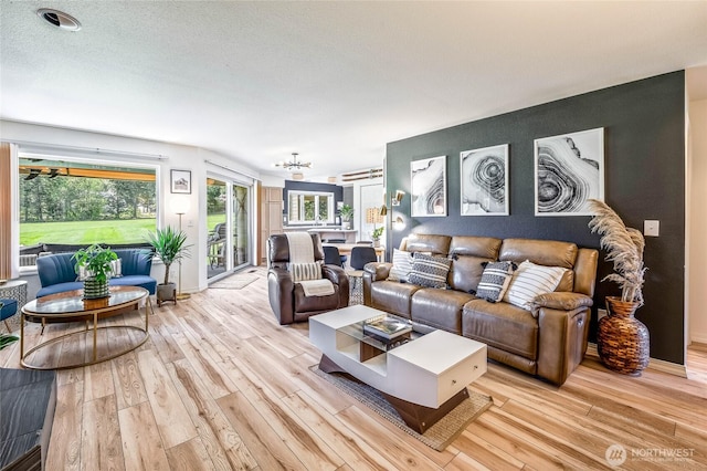 living area featuring light wood-style floors, a chandelier, and baseboards