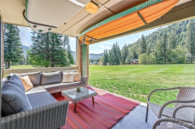 view of patio / terrace featuring an outdoor living space, a view of trees, and a mountain view