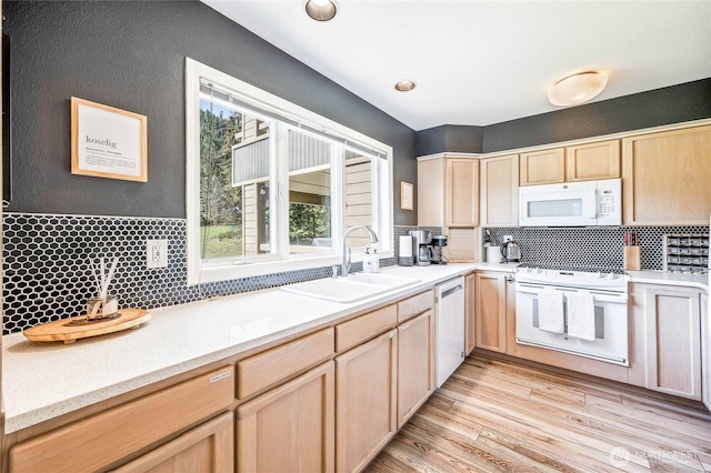 kitchen with white appliances, a sink, light brown cabinets, and backsplash