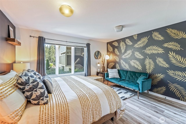 bedroom with wood finished floors and an accent wall