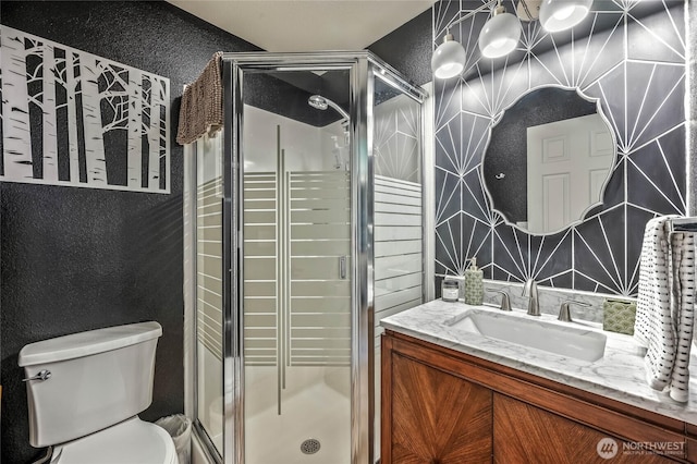 bathroom with toilet, a shower stall, and vanity