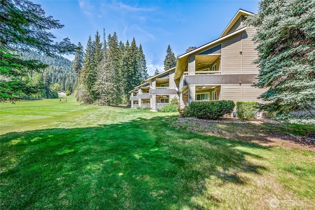 view of grassy yard featuring a balcony