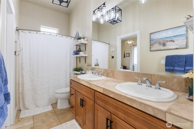 bathroom with a sink, tile patterned flooring, toilet, and double vanity