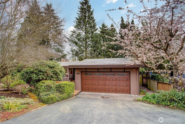 garage with aphalt driveway and fence