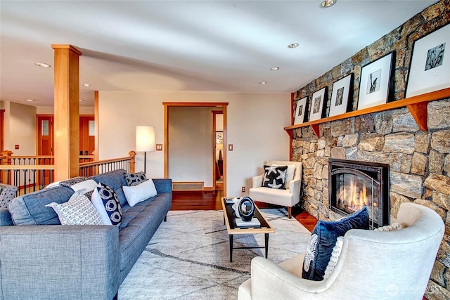 living room with recessed lighting, a stone fireplace, and wood finished floors
