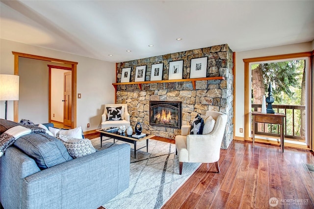 living room with baseboards, recessed lighting, wood finished floors, and a stone fireplace