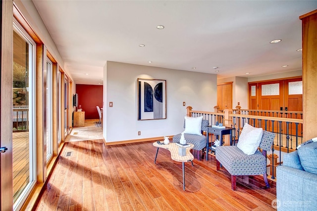 living area with recessed lighting, visible vents, baseboards, and light wood-type flooring