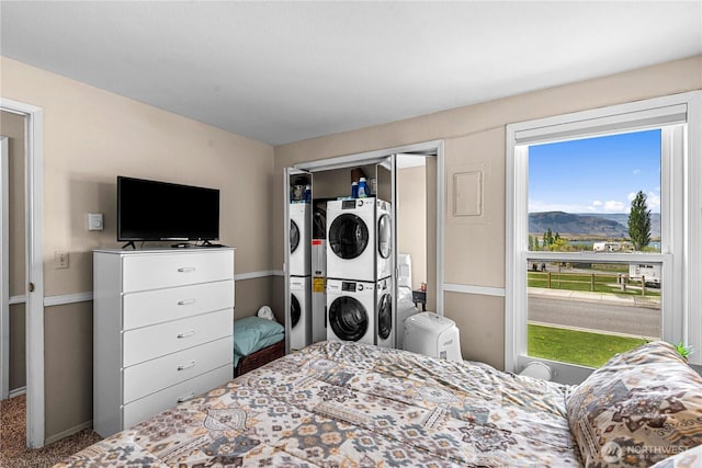 bedroom with a closet, a mountain view, carpet flooring, stacked washing maching and dryer, and baseboards