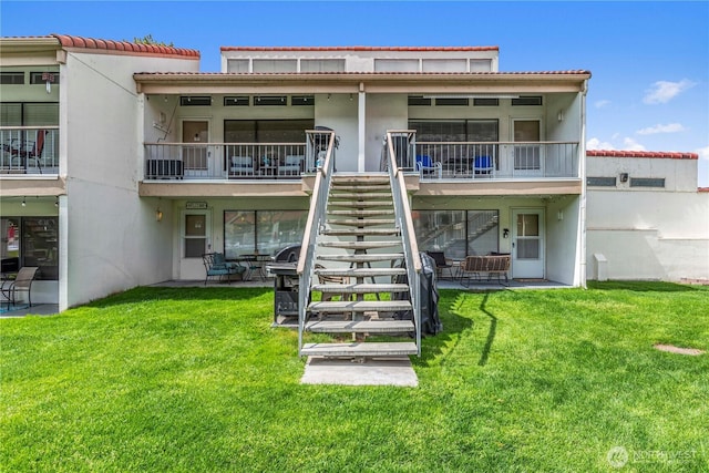 back of property featuring stairway, a patio area, stucco siding, and a yard