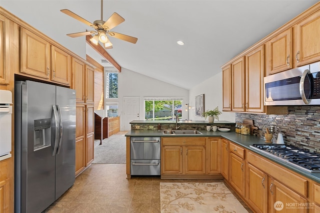 kitchen with dark countertops, vaulted ceiling, a sink, a peninsula, and stainless steel appliances
