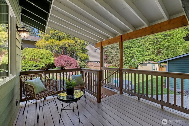 wooden deck featuring fence, an outdoor structure, and a shed