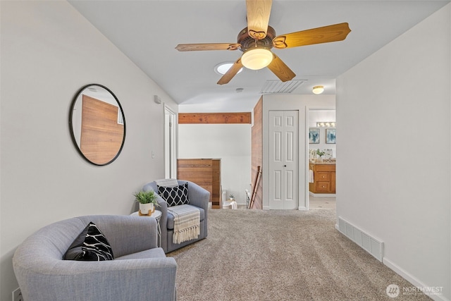 living area featuring visible vents, baseboards, ceiling fan, carpet flooring, and an upstairs landing