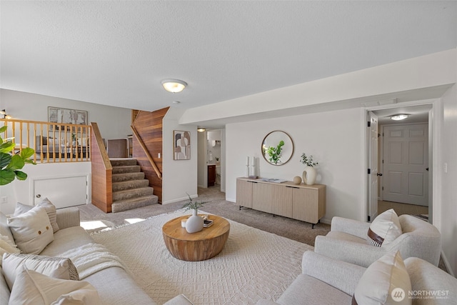 carpeted living room featuring stairs, a textured ceiling, and visible vents