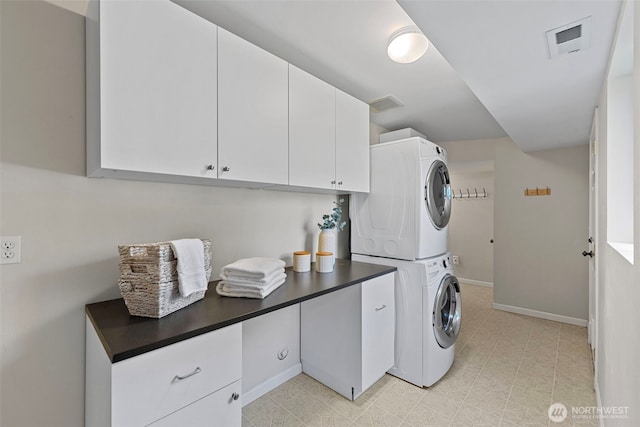 laundry room with stacked washing maching and dryer, baseboards, cabinet space, and visible vents