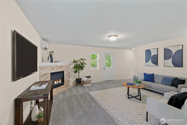 living room featuring baseboards, a wall mounted AC, carpet flooring, and a stone fireplace