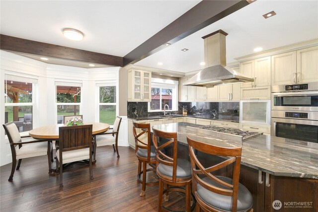 26217 137th Street Ct E, Buckley, WA 98321 - kitchen featuring appliances with stainless steel finishes, a sink, cream cabinetry, island exhaust hood, and tasteful backsplash