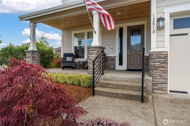 view of exterior entry featuring stone siding and a porch
