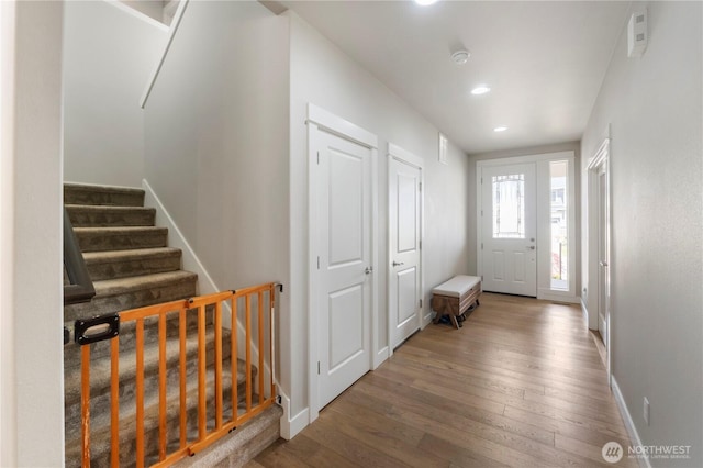 foyer featuring hardwood / wood-style flooring, baseboards, recessed lighting, and stairs