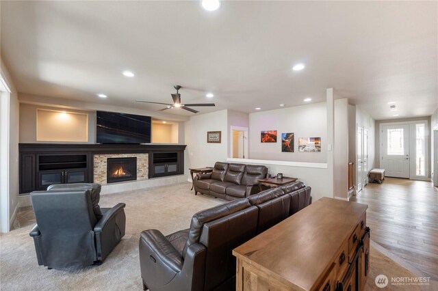 living area with a glass covered fireplace, a ceiling fan, recessed lighting, and light wood-style floors