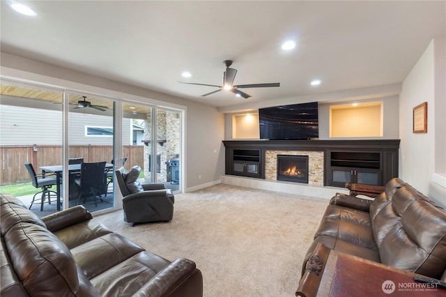 living area with a ceiling fan, recessed lighting, carpet flooring, a glass covered fireplace, and baseboards