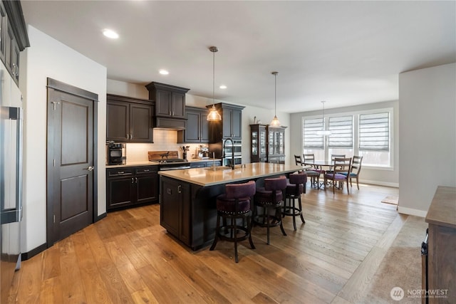 kitchen with a sink, a breakfast bar area, light wood finished floors, light countertops, and recessed lighting