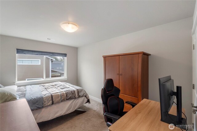carpeted bedroom featuring an office area and baseboards