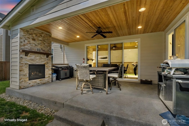 view of patio featuring an outdoor stone fireplace, outdoor dining space, and a ceiling fan