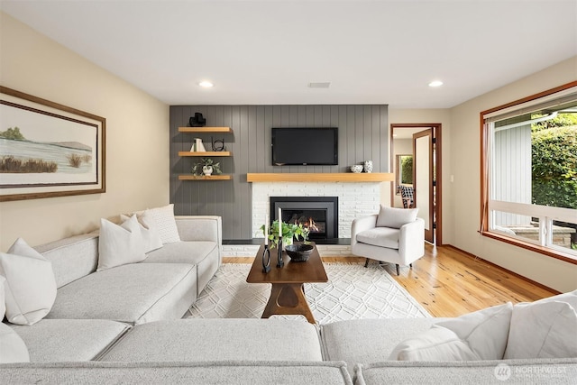 living room featuring a brick fireplace, recessed lighting, and wood finished floors