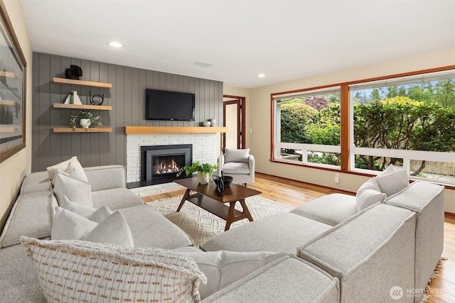 living room featuring recessed lighting, light wood-style flooring, and a fireplace