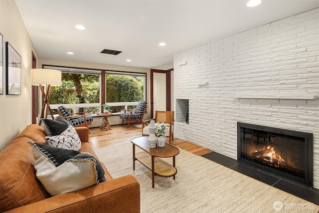 living area with a large fireplace, recessed lighting, wood finished floors, and visible vents