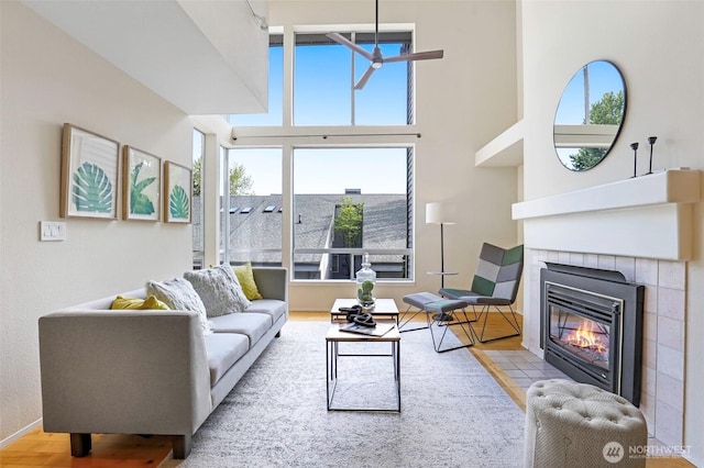 living room with a tiled fireplace, wood finished floors, and a healthy amount of sunlight