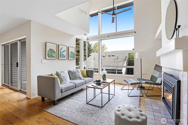 living room featuring baseboards, a towering ceiling, hardwood / wood-style floors, and a tile fireplace