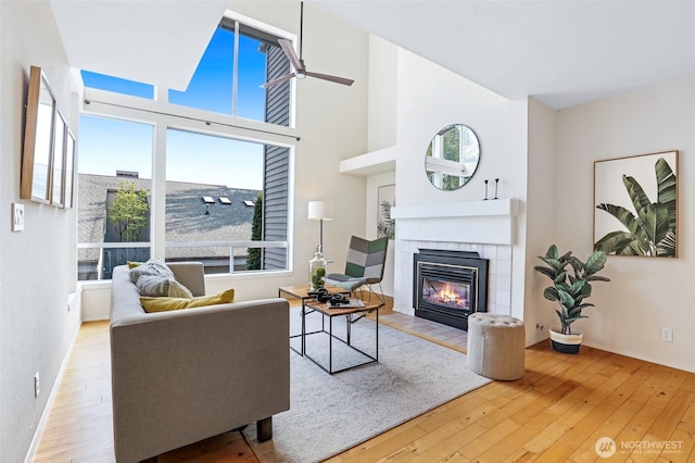 living area featuring a towering ceiling, hardwood / wood-style floors, and a tile fireplace
