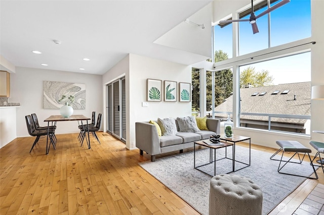 living area with recessed lighting, a high ceiling, and light wood finished floors