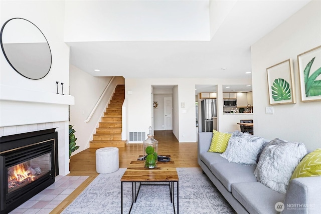 living area with stairway, a fireplace, wood finished floors, and visible vents