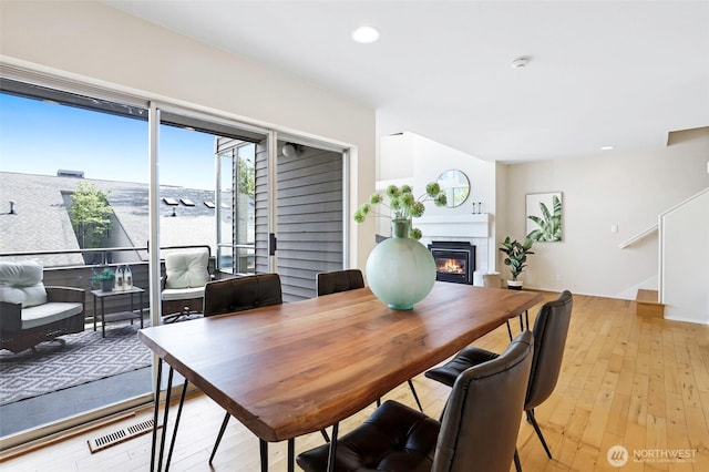 dining room with a glass covered fireplace, light wood-style floors, recessed lighting, and visible vents
