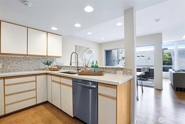 kitchen with a sink, a wealth of natural light, tasteful backsplash, and dishwasher