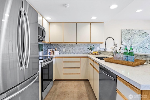 kitchen with tasteful backsplash, cream cabinets, a sink, stainless steel appliances, and recessed lighting
