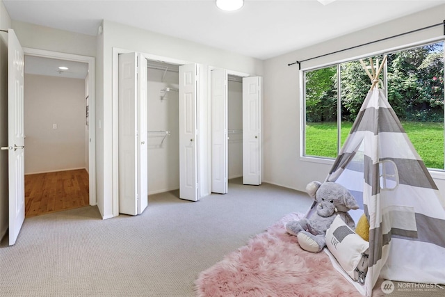 bedroom featuring multiple closets and light colored carpet