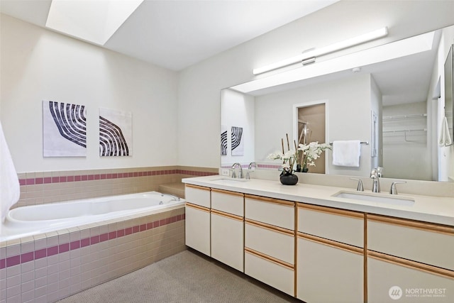 bathroom with double vanity, a sink, a walk in closet, and a bath