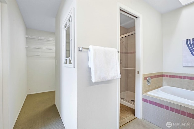 full bathroom featuring a shower stall, a garden tub, and a spacious closet