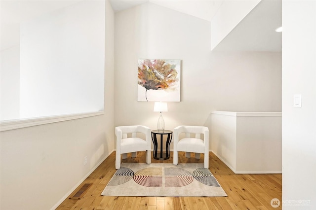 living area featuring baseboards, hardwood / wood-style flooring, and visible vents