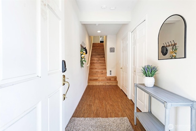hallway featuring recessed lighting, wood finished floors, and stairway