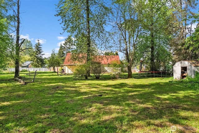 view of yard featuring a trampoline and fence