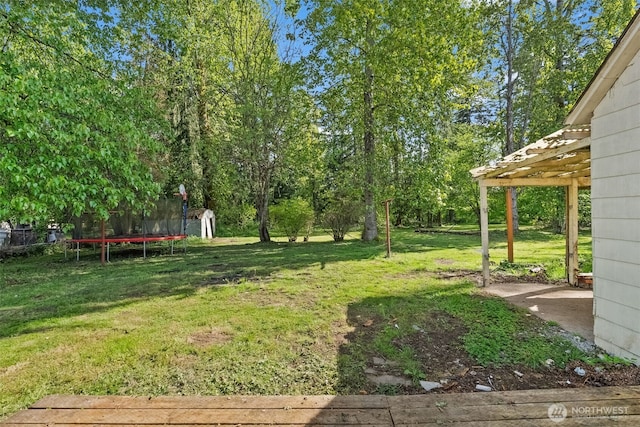view of yard with a trampoline and a pergola