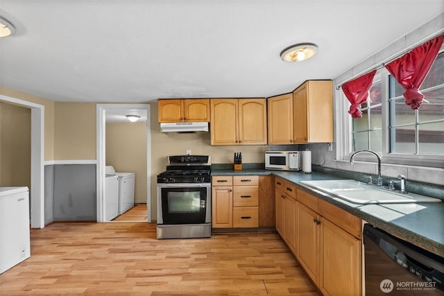 kitchen featuring white microwave, stainless steel gas range, under cabinet range hood, washing machine and clothes dryer, and dishwasher