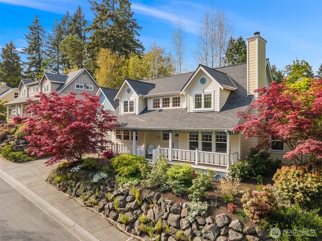 view of front of home featuring a porch, a chimney, and a shingled roof