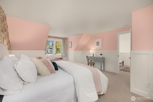 bedroom featuring carpet floors, wainscoting, and a decorative wall